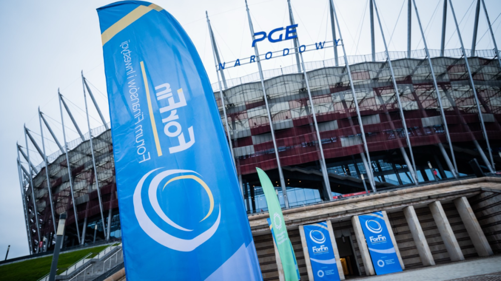 ForFin 2025 konferencja - PGE Narodowy w Warszawie, niebieskie banery i flagi z logiem ForFin Forum Finansów i Inwestycji, wejście na stadion, miejsce odbywającego się bezpłatnego wydarzenia edukacyjnego o finansach